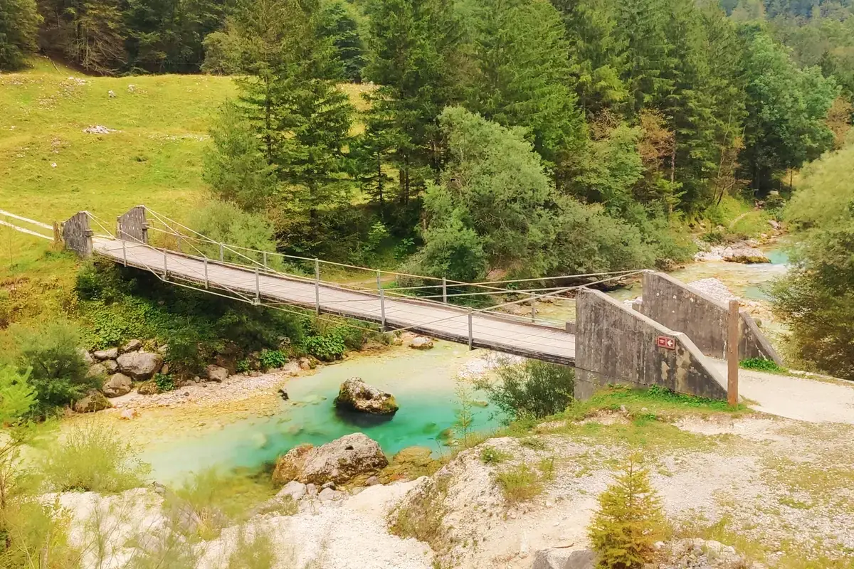 Wooden suspension bridge over the Soča River with turquoise water in Slovenia